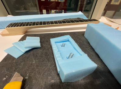 Placeholder text — early foam prototyping, blocking out the proportions of the neck and body in blue foam to test grip and scale by hand.