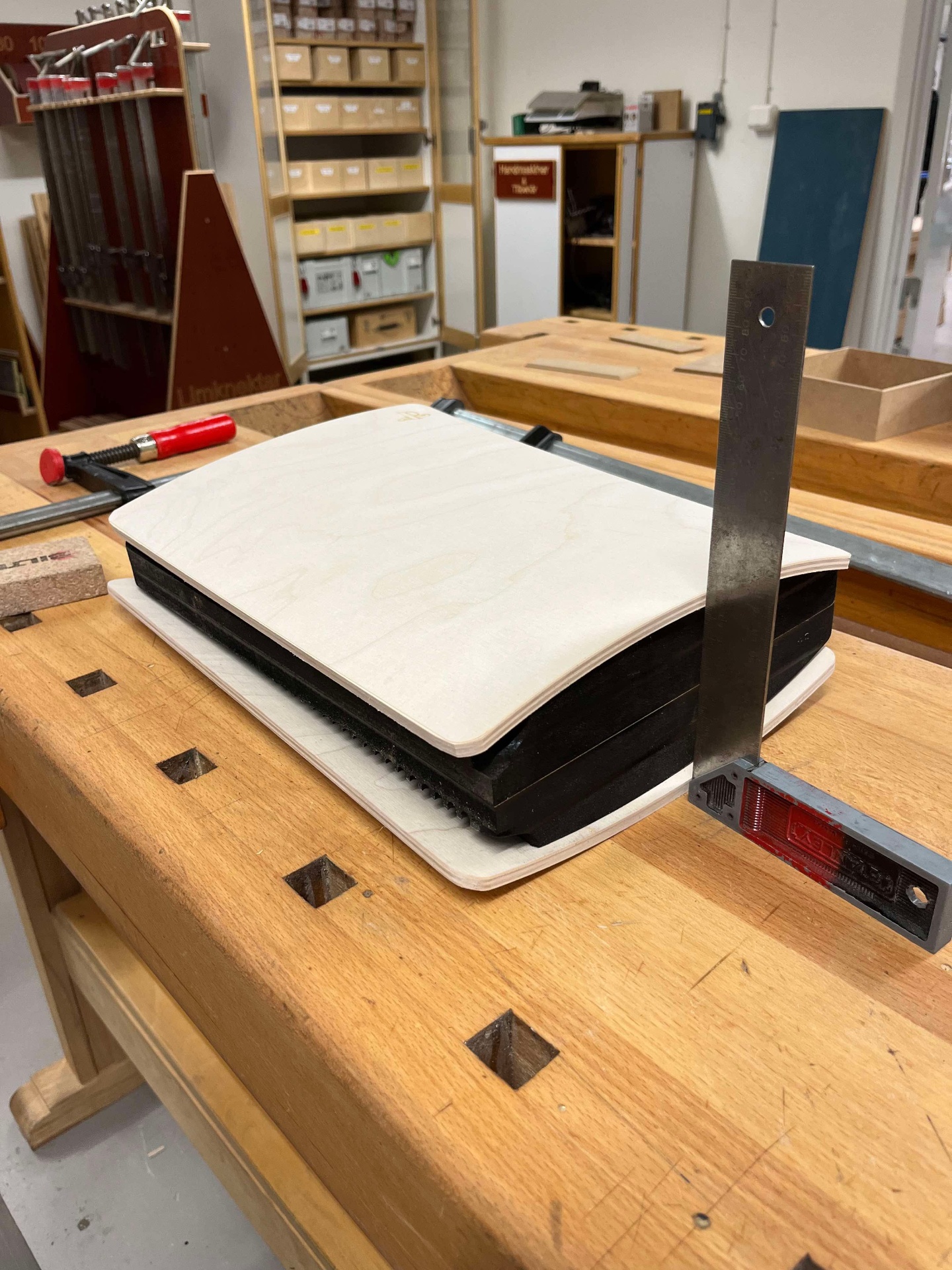 Placeholder text — trial fit on the workbench, checking the curvature of the freshly pressed birch faceplate against the chassis with a square.